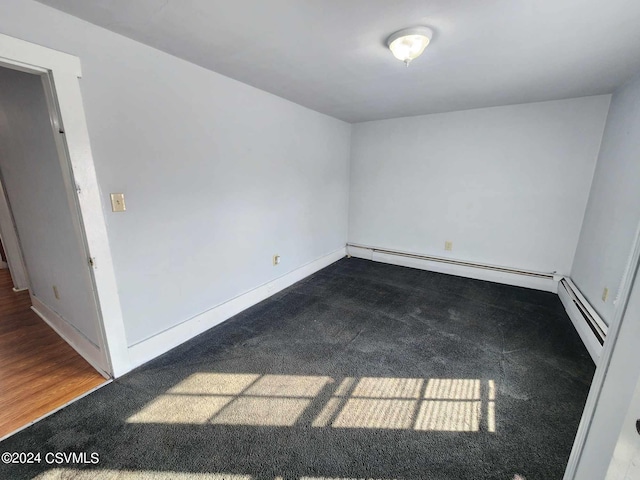 spare room featuring baseboard heating and wood-type flooring