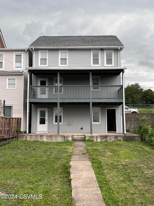 back of property with a lawn and a balcony