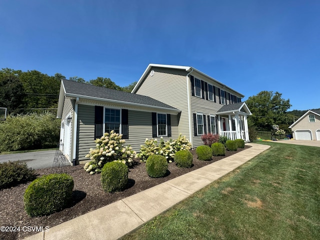 view of front of property featuring a garage, a porch, and a front lawn