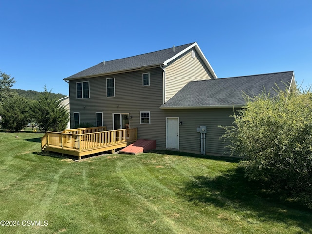 rear view of property with a wooden deck and a lawn