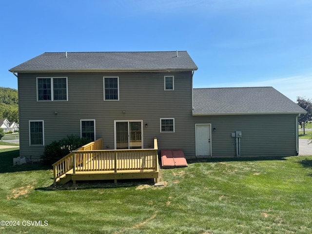 back of property featuring a wooden deck and a lawn