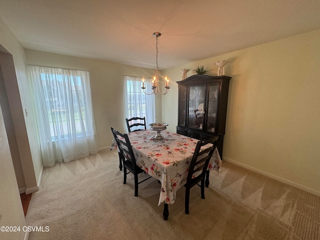 dining space featuring light colored carpet and a chandelier