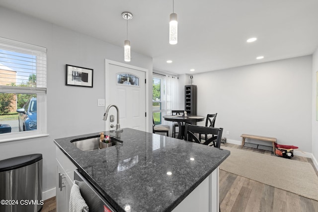 kitchen featuring dark stone countertops, a wealth of natural light, light hardwood / wood-style floors, and sink