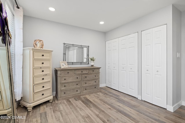 bedroom with multiple closets and hardwood / wood-style flooring