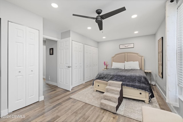 bedroom featuring ceiling fan, light hardwood / wood-style floors, and multiple closets