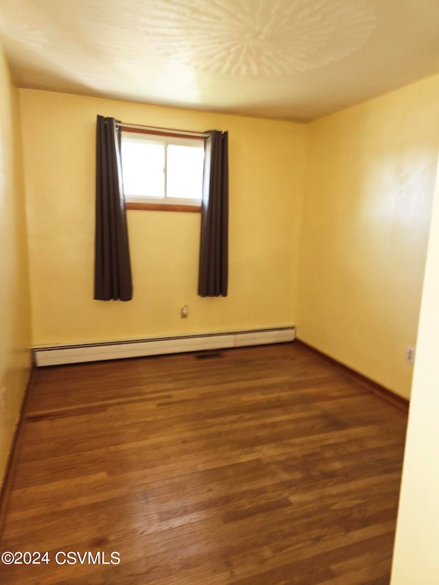 unfurnished room with a baseboard radiator and hardwood / wood-style floors