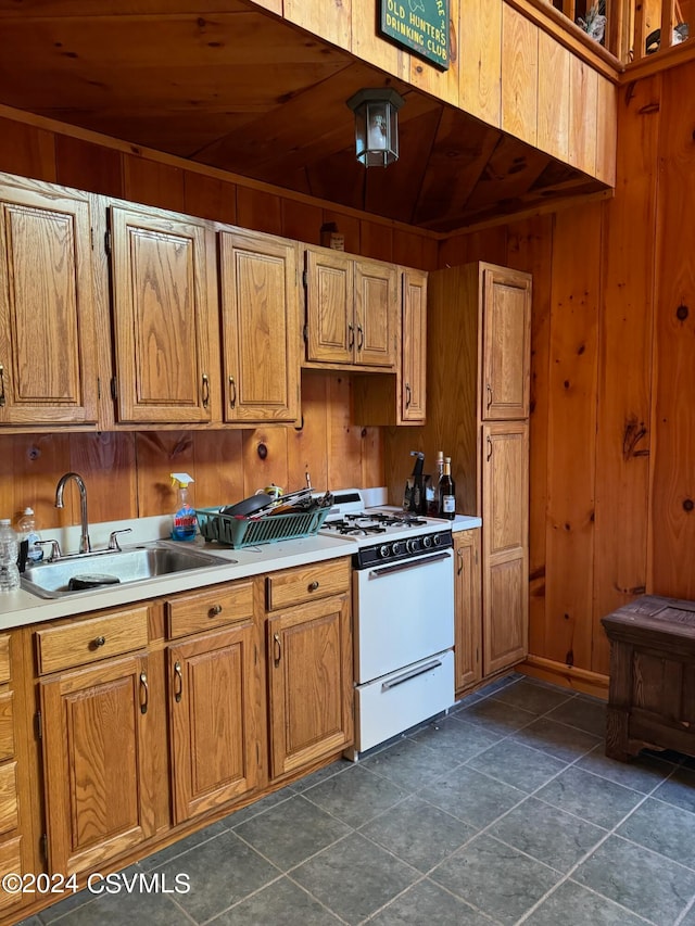 kitchen featuring dark tile patterned floors, wooden ceiling, sink, wooden walls, and white range oven