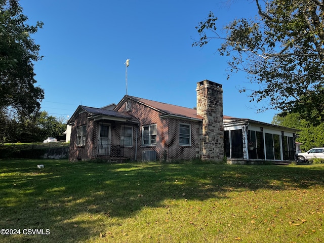 rear view of house featuring a yard, cooling unit, and a sunroom