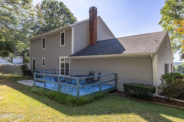 rear view of property with a garage, a wooden deck, and a lawn