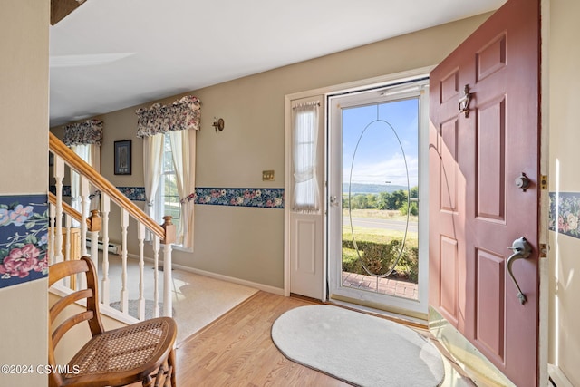 foyer entrance with a baseboard radiator, plenty of natural light, and light hardwood / wood-style floors