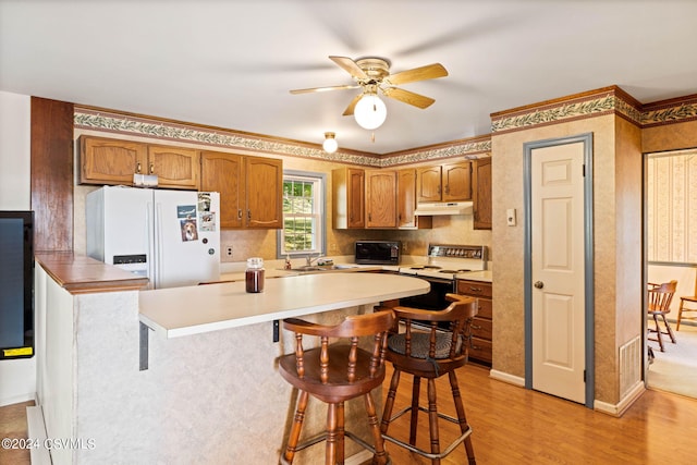 kitchen with ceiling fan, a breakfast bar, white fridge with ice dispenser, electric stove, and light wood-type flooring