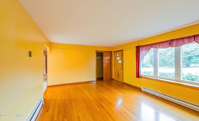 empty room featuring baseboard heating and hardwood / wood-style flooring