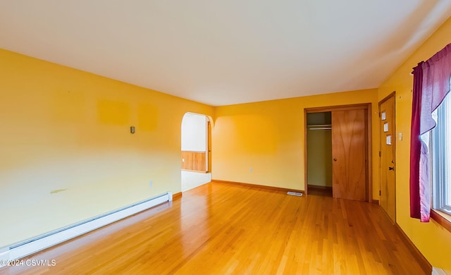 empty room with wood-type flooring and baseboard heating