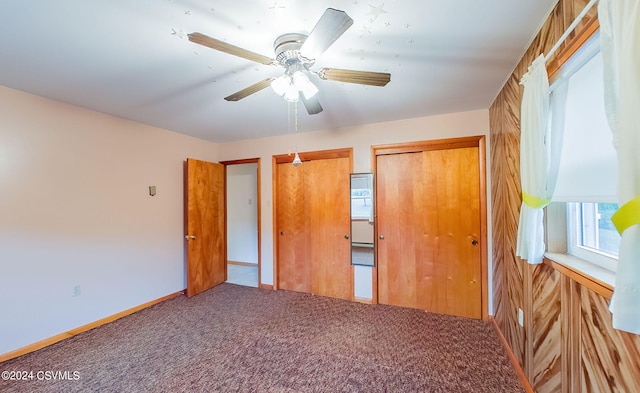 unfurnished bedroom with wood walls, ceiling fan, and carpet flooring