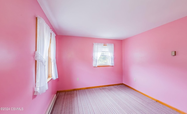 carpeted empty room featuring a baseboard heating unit