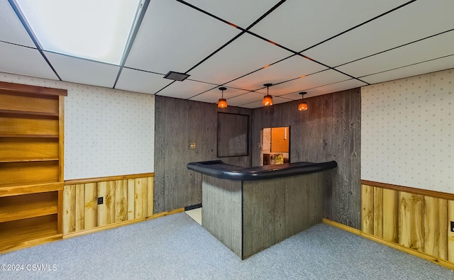 bar featuring wood walls, carpet floors, and a paneled ceiling