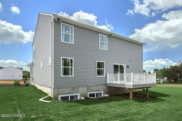 rear view of property featuring a wooden deck and a lawn