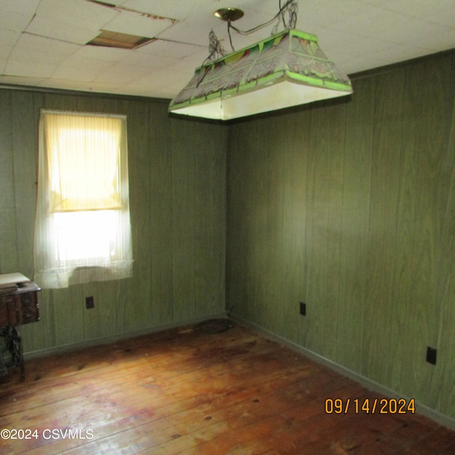 unfurnished room featuring wooden walls and hardwood / wood-style flooring