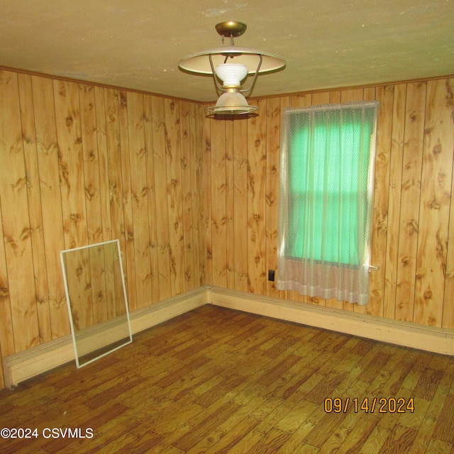 unfurnished room with hardwood / wood-style floors and wood walls