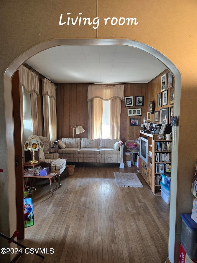 living room with wood-type flooring and wooden walls