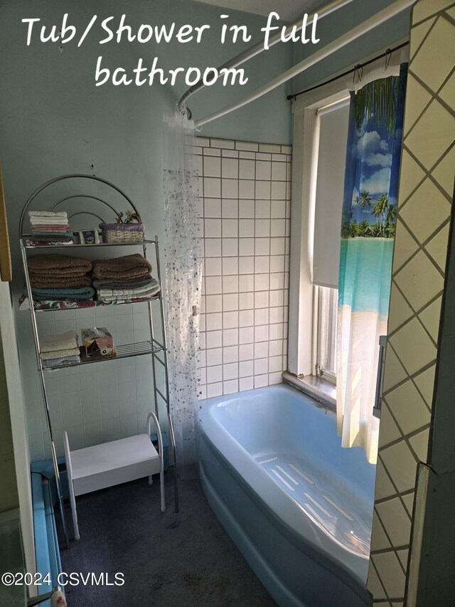 bathroom with tile walls and shower / bath combo with shower curtain