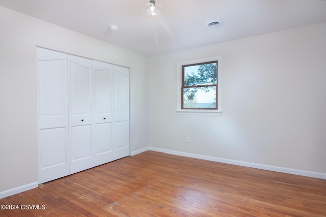 unfurnished bedroom with wood-type flooring and a closet