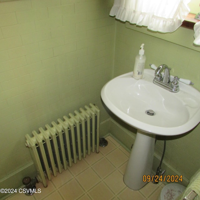 bathroom featuring radiator heating unit and tile walls