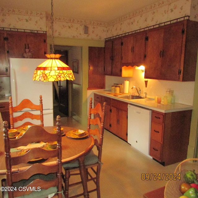 kitchen with white appliances, hanging light fixtures, and sink