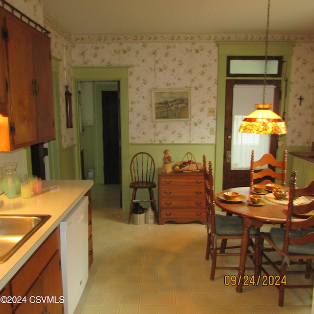 kitchen featuring hanging light fixtures, dishwasher, light tile patterned floors, and sink