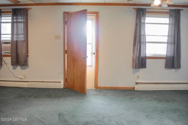 carpeted spare room featuring a healthy amount of sunlight, baseboard heating, and ceiling fan