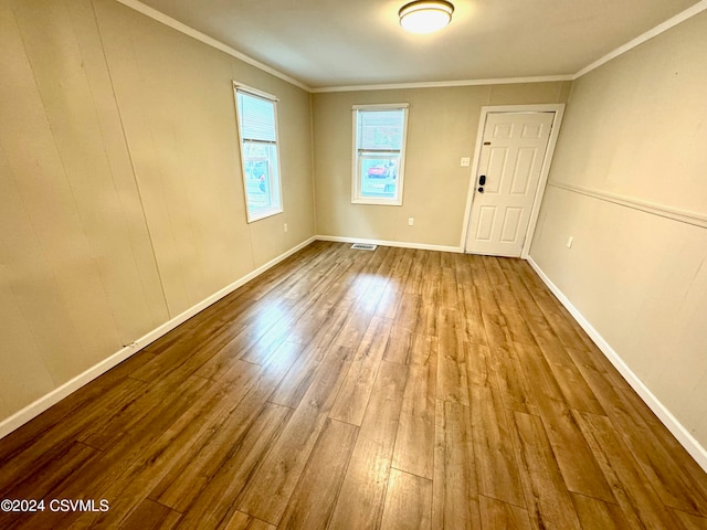 empty room with ornamental molding and hardwood / wood-style floors