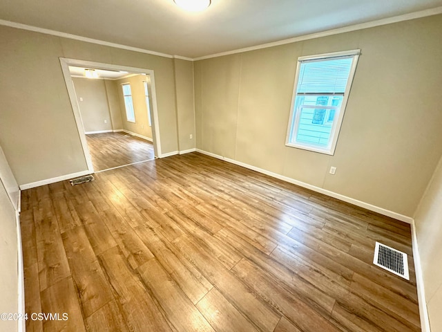 empty room with ornamental molding and hardwood / wood-style flooring