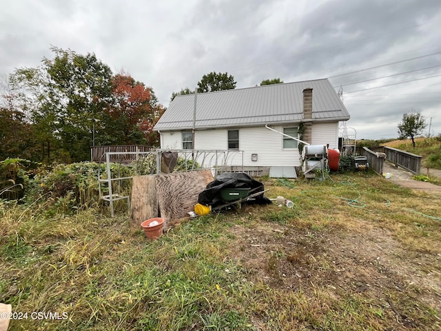 rear view of property featuring fence and metal roof