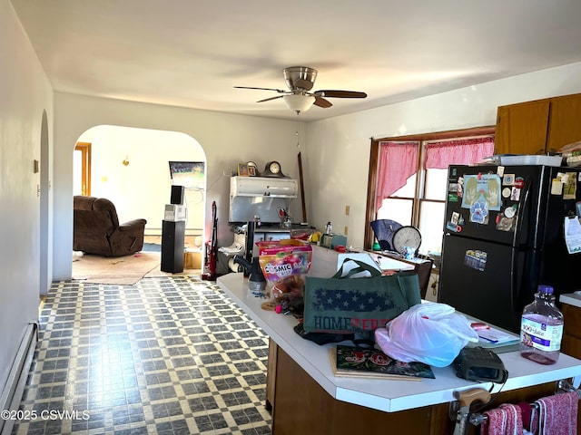 office area featuring arched walkways, baseboard heating, and a ceiling fan