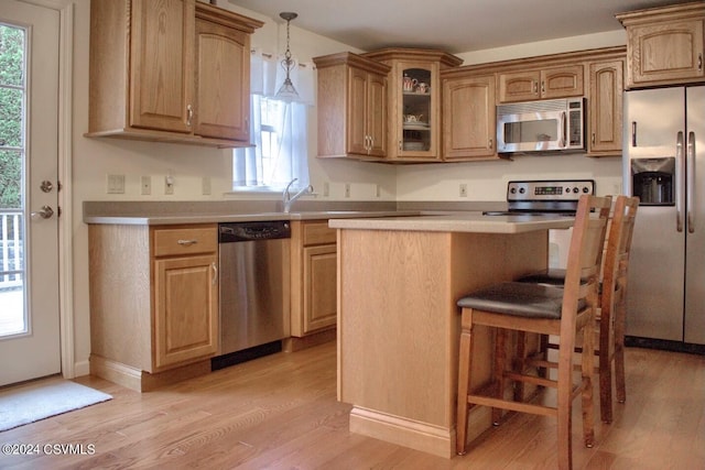 kitchen featuring decorative light fixtures, light hardwood / wood-style flooring, stainless steel appliances, and plenty of natural light