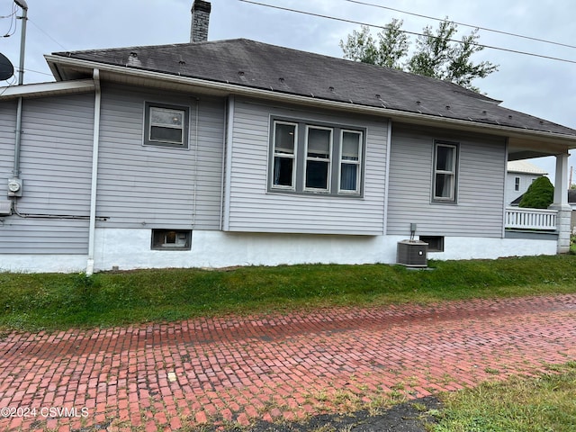 rear view of house featuring central AC unit and a yard