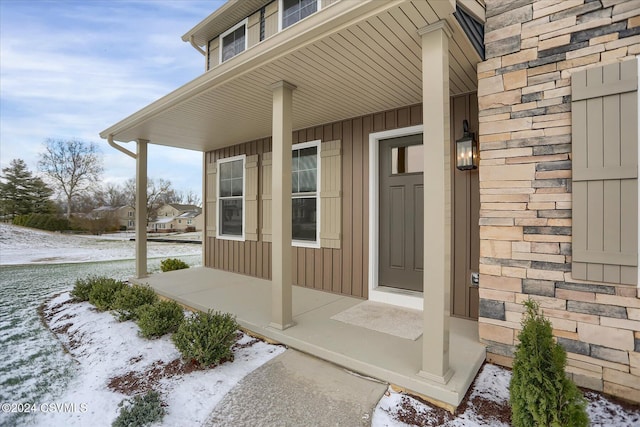 snow covered property entrance featuring a porch