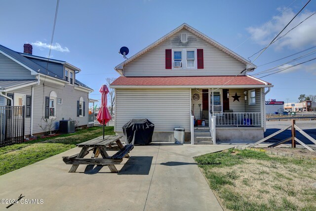 view of front of house with a front lawn, central AC unit, and covered porch