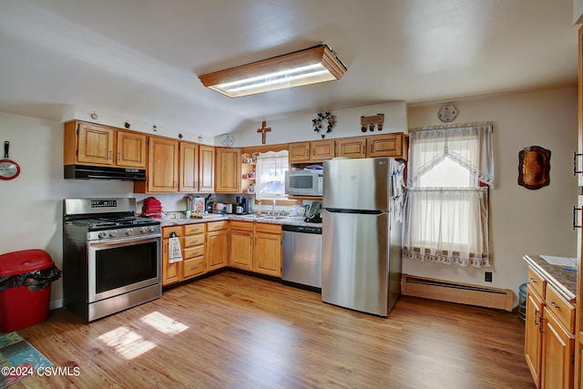 kitchen with lofted ceiling, baseboard heating, stainless steel appliances, and a wealth of natural light