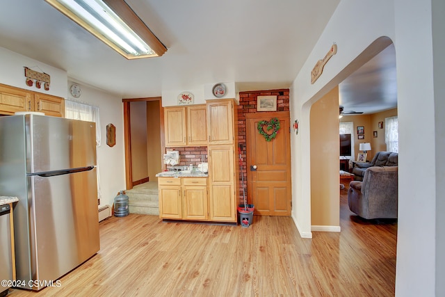 kitchen with appliances with stainless steel finishes, decorative backsplash, light brown cabinets, ceiling fan, and light hardwood / wood-style flooring