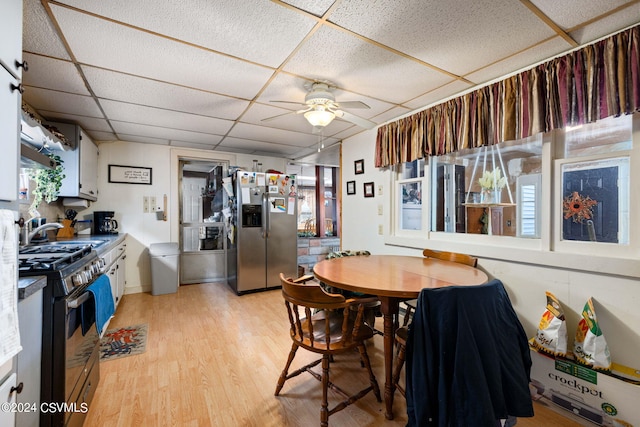 dining space featuring light hardwood / wood-style flooring, ceiling fan, a drop ceiling, and sink