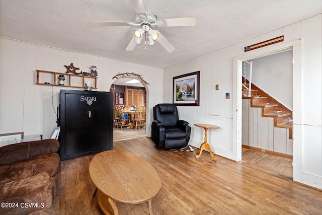 interior space featuring a textured ceiling, wood walls, hardwood / wood-style floors, and ceiling fan