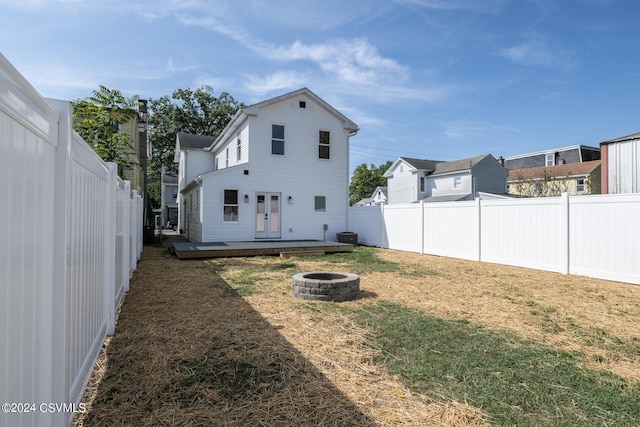 back of house featuring central AC, a wooden deck, a yard, and an outdoor fire pit