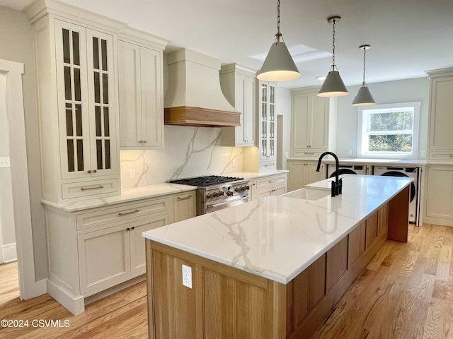 kitchen featuring light wood-type flooring, sink, custom exhaust hood, and a spacious island