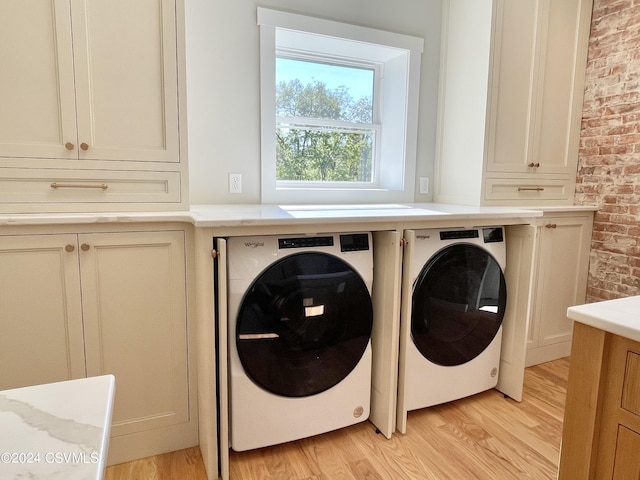 clothes washing area featuring separate washer and dryer, light hardwood / wood-style flooring, and brick wall