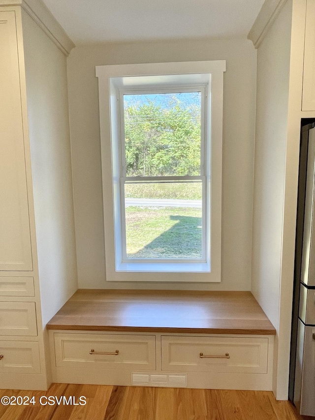 interior space with light hardwood / wood-style flooring, white cabinets, and stainless steel fridge