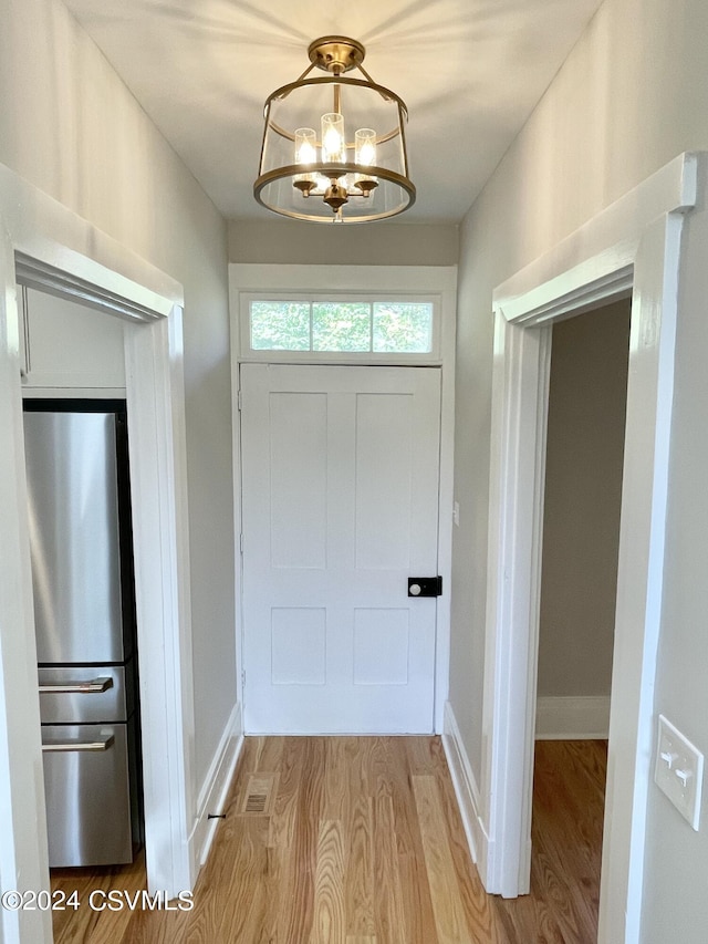 doorway to outside featuring light wood-type flooring and a chandelier