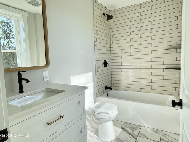 full bathroom featuring vanity, tiled shower / bath combo, and toilet