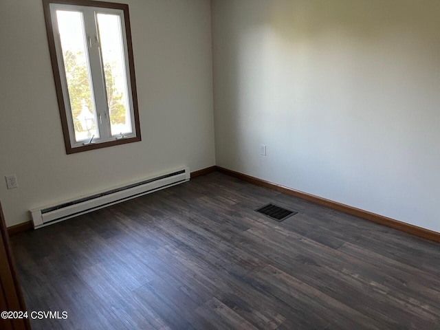 empty room with dark wood-type flooring and a baseboard heating unit