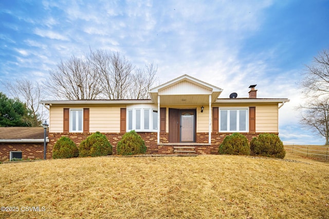 single story home featuring brick siding, fence, a chimney, and a front lawn